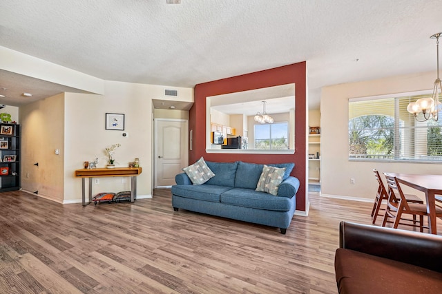 living room featuring a textured ceiling, hardwood / wood-style flooring, and a notable chandelier