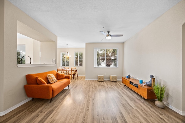 living area with hardwood / wood-style flooring, ceiling fan with notable chandelier, and a textured ceiling