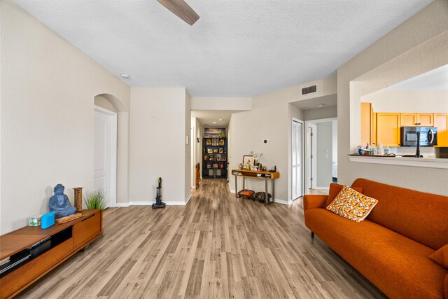 living room with a textured ceiling, ceiling fan with notable chandelier, and hardwood / wood-style flooring