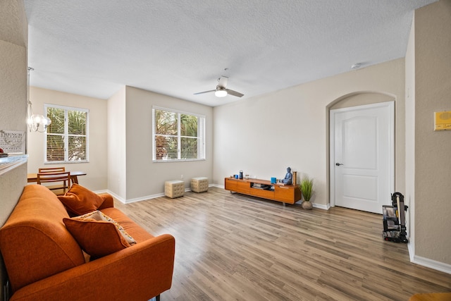 sitting room featuring a healthy amount of sunlight, ceiling fan with notable chandelier, a textured ceiling, and light hardwood / wood-style floors