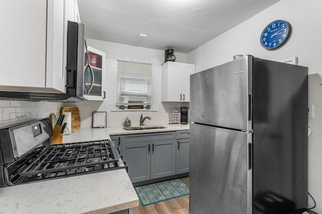 kitchen with gray cabinets, white cabinets, appliances with stainless steel finishes, wood-type flooring, and sink