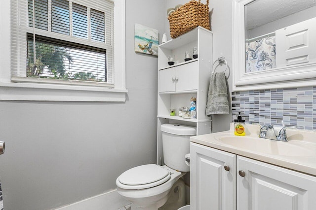 bathroom with vanity, decorative backsplash, and toilet