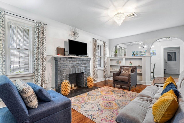 living room featuring a fireplace, wood-type flooring, and a healthy amount of sunlight