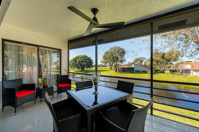 sunroom featuring a water view and ceiling fan