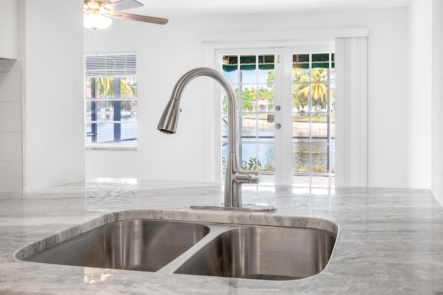 interior details featuring light stone countertops, ceiling fan, and sink