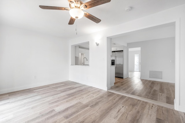 empty room with light hardwood / wood-style flooring, ceiling fan, and sink