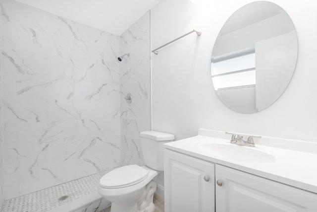 bathroom with vanity, toilet, and tiled shower