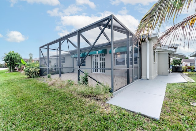 back of house featuring a lawn, glass enclosure, cooling unit, and a patio