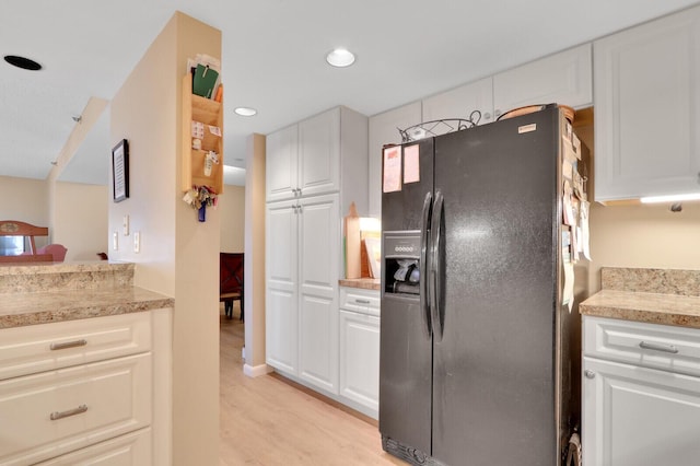 kitchen featuring light hardwood / wood-style floors, white cabinetry, and black refrigerator with ice dispenser