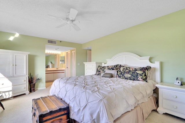 bedroom featuring connected bathroom, ceiling fan, light colored carpet, and a textured ceiling