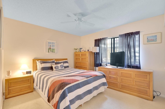 carpeted bedroom featuring ceiling fan and a textured ceiling