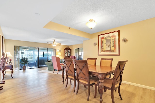 dining area with ceiling fan, light wood-type flooring, and a textured ceiling