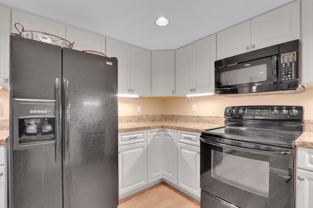 kitchen featuring white cabinets, light wood-type flooring, and black appliances