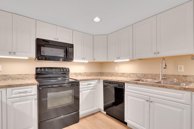 kitchen with black appliances, white cabinets, sink, and light hardwood / wood-style flooring