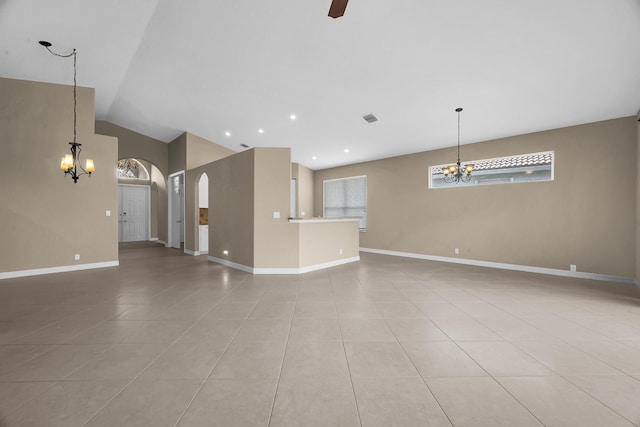 unfurnished living room featuring baseboards, vaulted ceiling, light tile patterned floors, ceiling fan with notable chandelier, and arched walkways