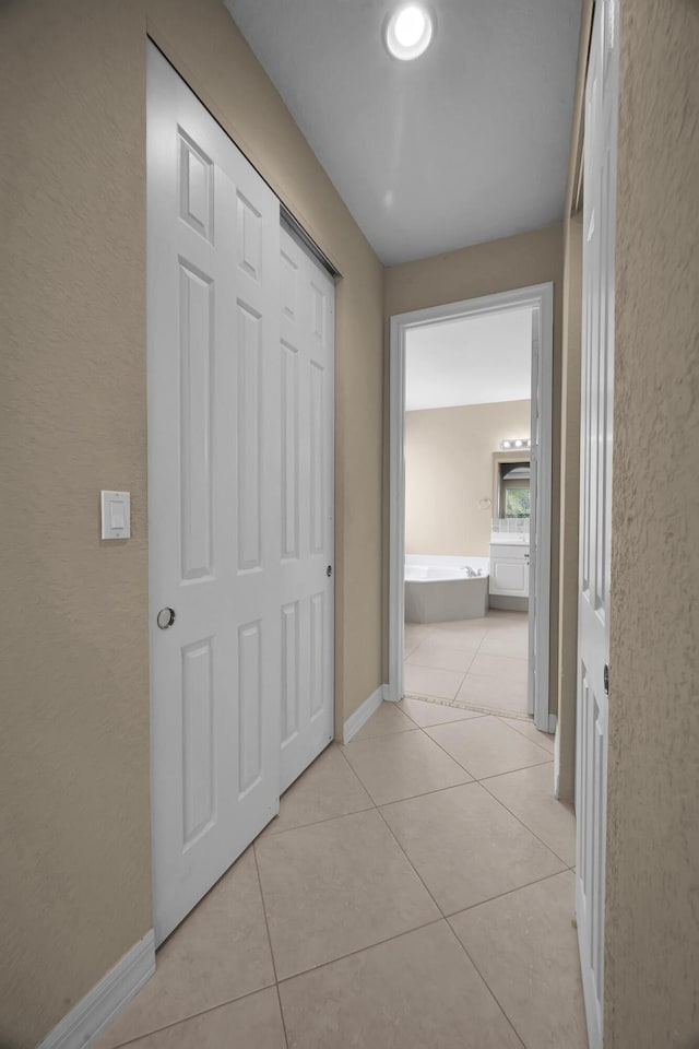 hallway with light tile patterned floors and baseboards