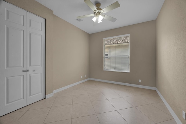 unfurnished room with light tile patterned floors, visible vents, baseboards, and ceiling fan