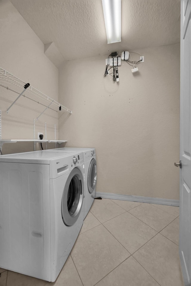 laundry room with baseboards, light tile patterned floors, laundry area, independent washer and dryer, and a textured ceiling