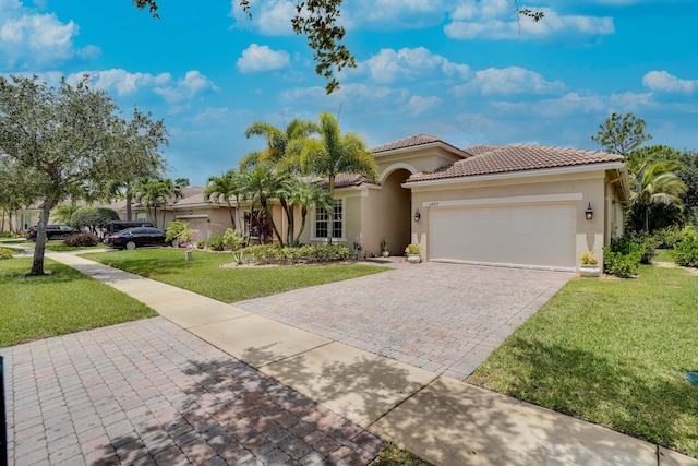 mediterranean / spanish home with stucco siding, a front lawn, a tile roof, decorative driveway, and an attached garage