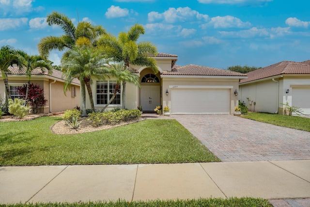 view of front of house featuring stucco siding, a front lawn, a tile roof, decorative driveway, and an attached garage