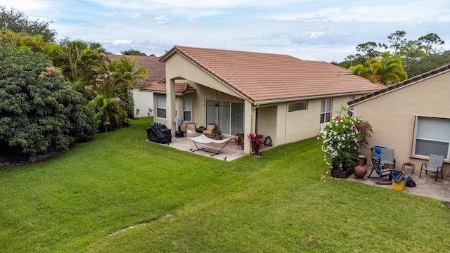 back of house with a patio, a lawn, and a tiled roof