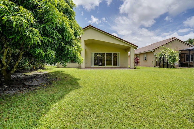 back of property with stucco siding and a yard