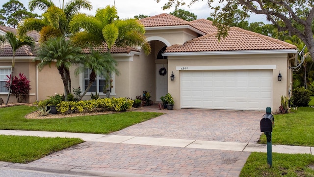 view of front facade with stucco siding, a tile roof, decorative driveway, a front yard, and a garage