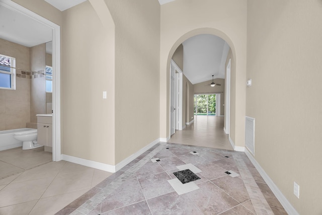 hallway with tile patterned floors, baseboards, arched walkways, and visible vents