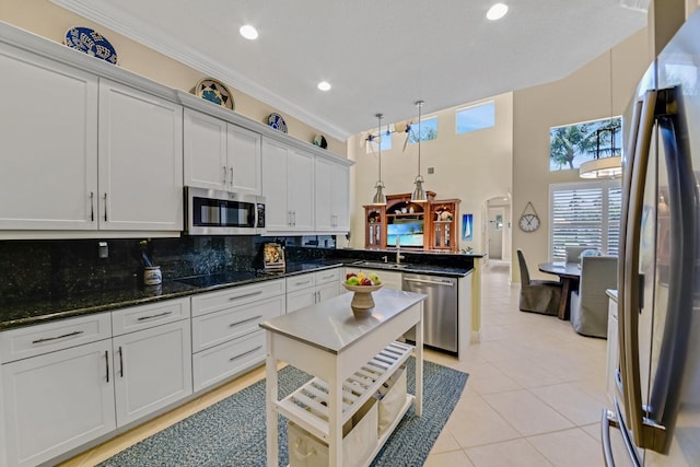 kitchen featuring tasteful backsplash, stainless steel appliances, light tile patterned floors, white cabinetry, and hanging light fixtures