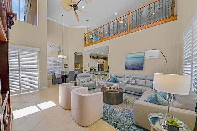 tiled living room featuring ceiling fan, a towering ceiling, and crown molding