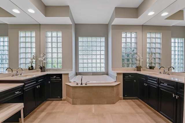 bathroom featuring tile patterned floors, a relaxing tiled tub, and vanity