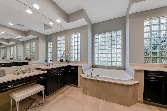 bathroom with tile patterned flooring, vanity, and tiled tub