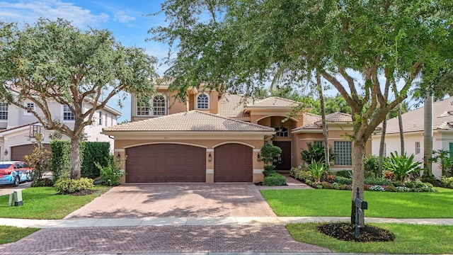 mediterranean / spanish-style home with a garage and a front lawn