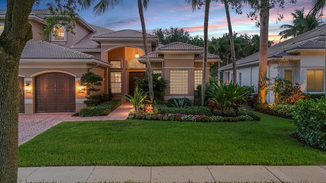 mediterranean / spanish-style home featuring a garage and a lawn