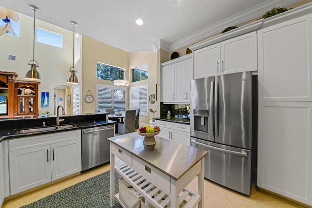 kitchen with white cabinets, decorative backsplash, stainless steel appliances, and hanging light fixtures