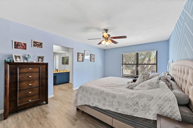 bedroom with light wood-type flooring, a textured ceiling, connected bathroom, and ceiling fan