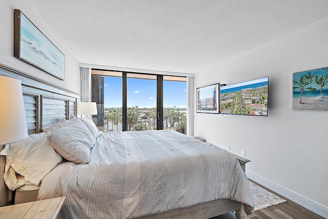 bedroom featuring a textured ceiling, hardwood / wood-style floors, access to outside, and expansive windows