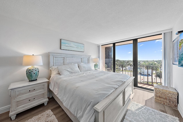 bedroom with a textured ceiling, access to exterior, floor to ceiling windows, and light hardwood / wood-style flooring