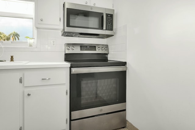 kitchen with tasteful backsplash, white cabinets, and stainless steel appliances