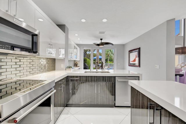 kitchen with decorative backsplash, stainless steel appliances, sink, white cabinetry, and light tile patterned flooring