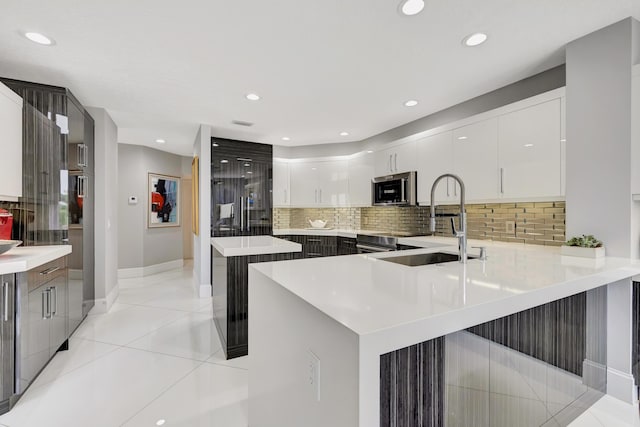 kitchen featuring white cabinets, sink, tasteful backsplash, light tile patterned flooring, and kitchen peninsula