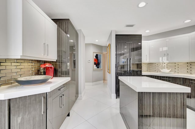 kitchen with white cabinetry, a kitchen island, tasteful backsplash, and light tile patterned flooring