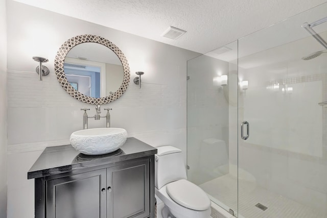 bathroom featuring vanity, a textured ceiling, toilet, and walk in shower