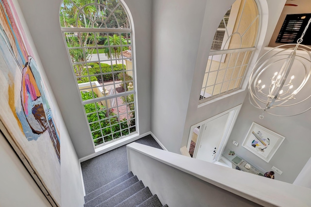 staircase with carpet floors, plenty of natural light, and a notable chandelier