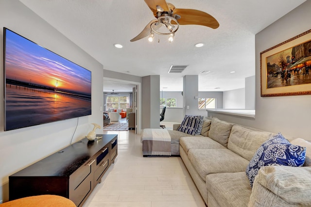 living room with ceiling fan and a textured ceiling