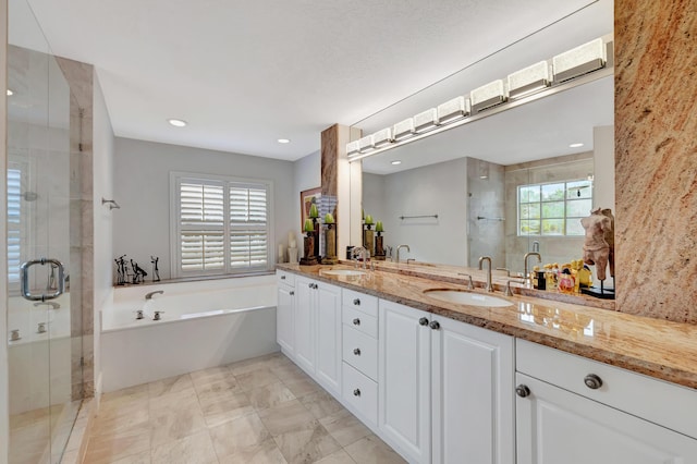 bathroom with plus walk in shower, vanity, and a healthy amount of sunlight