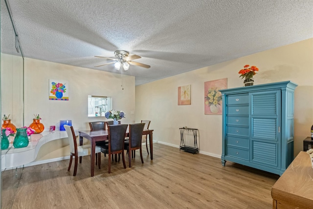 dining room with ceiling fan, light wood-type flooring, and a textured ceiling