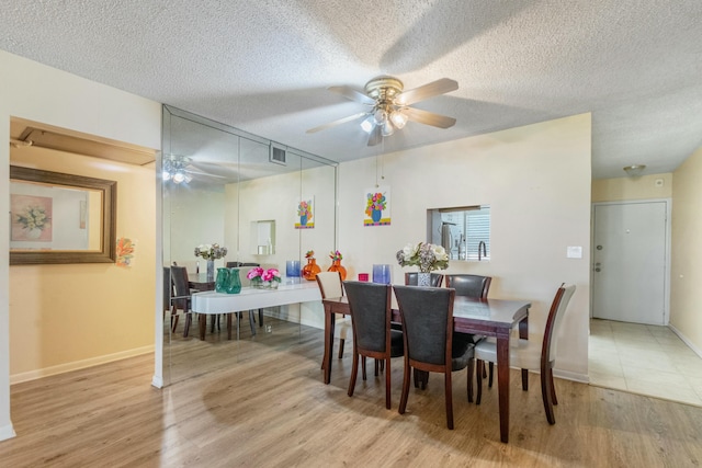 dining room with ceiling fan, light hardwood / wood-style flooring, and a textured ceiling