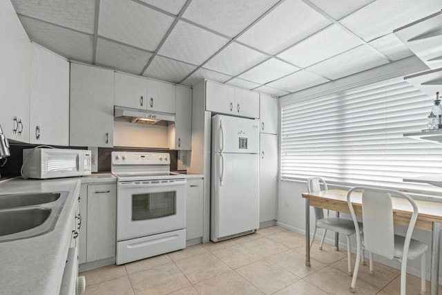 kitchen with white cabinetry, sink, a drop ceiling, white appliances, and light tile patterned floors