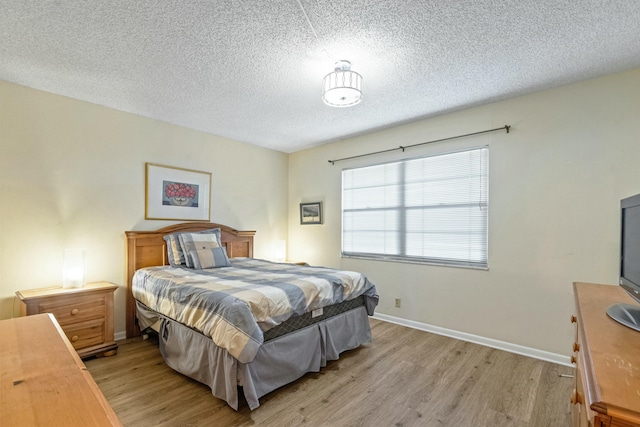 bedroom featuring light hardwood / wood-style floors and a textured ceiling